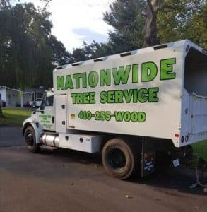 A truck labeled "Nationwide Tree Service," a local tree service, with contact number 410-255-WOOD, parked on a residential street.